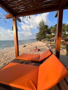 an orange bench on a beach with people on the sand at Rajapruek Samui Resort - SHA Plus in Lipa Noi