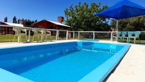 una piscina azul con sillas y sombrilla en Cabañas Los Viñedos en San Rafael