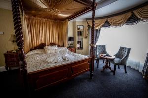 een slaapkamer met een hemelbed en een tafel en stoelen bij Kings Croft Hotel in Pontefract