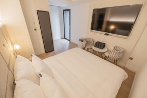 1 dormitorio con 1 cama blanca y TV en Denbasta Hotel Heritage en Gyeongju