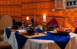 einen Tisch mit einem blauen Tischtuch und Kerzen darauf in der Unterkunft Camp Desert Trips in M’hamid El Ghizlane