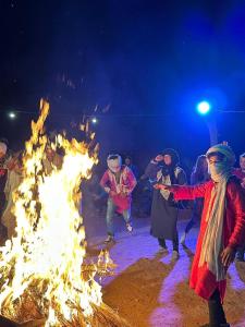 Un gruppo di persone che ballano intorno al fuoco di Chegaga Desert Trips a M'Hamid