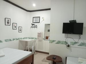 a white room with a table and a tv on the wall at Ennas Place in Coron