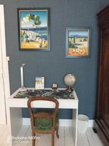 - un bureau avec une chaise à côté d'un mur orné de peintures dans l'établissement Chambre Bounty cuisine privée, salle d'eau, terrasse, garage, à Olliergues