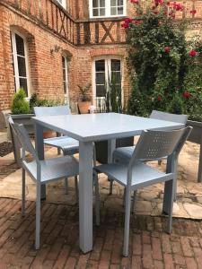 una mesa blanca y sillas en un patio de ladrillo en Le Logis de Pélagie, en Neufchâtel-en-Bray