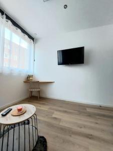 a room with a table and a tv on a wall at Studio confort #2, proche Gare et commodités in Maubeuge