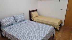 um quarto com uma cama, uma cama e uma almofada em Casa da Voh em Ilha Comprida