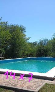 una piscina con sillas rosas frente a ella en Casa Dos, casita de campo en Alta Gracia