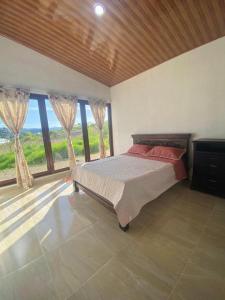 1 dormitorio con 1 cama en una habitación con ventanas en Cabañas Villa Victoria, en Sutamarchán