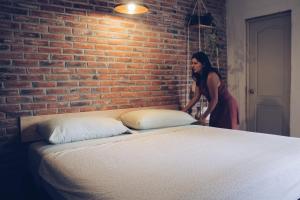 a woman standing next to a brick wall with a bed at Hoja Santa Posada in Cholula +135 photos