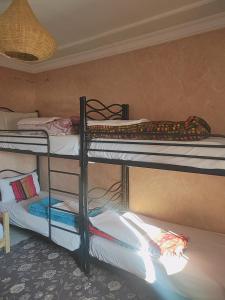 a room with three bunk beds in a room at Afgo Hostel in Ouarzazate