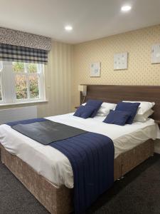 a bedroom with a large bed with blue pillows at Kings Croft Hotel in Pontefract