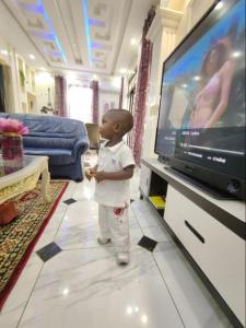 a little boy standing in front of a television at Résidence Chérel à Odza Minkan in Yaoundé