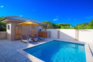 una piscina con 2 sillas y una sombrilla en Lovely Caribbean family villa with private pool en Willemstad