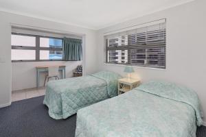 two beds in a room with two windows at Spinnaker Beach Front in Mooloolaba