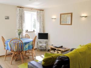 ein Wohnzimmer mit einem Sofa, einem Tisch und einem TV in der Unterkunft Primrose Cottage in Winterborne Steepleton