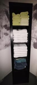 a black shelf with towels and folded towels at zu den blauen Schwertern in Meißen