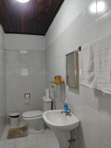 a white bathroom with a toilet and a sink at Casa Colonial no Centro in Carolina