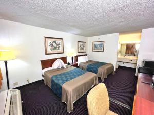 a hotel room with two beds and a television at Heritage Inn and Suites in Baton Rouge