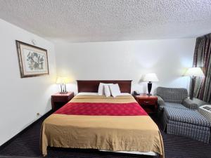 um quarto de hotel com uma cama e uma cadeira em Heritage Inn and Suites em Baton Rouge