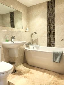 ein Badezimmer mit einem Waschbecken, einer Badewanne und einem WC in der Unterkunft 8 Oakridge, St Mellion in St Mellion