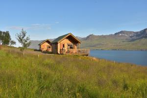 una cabaña de madera en una colina junto a un lago en Sólbrekka Holiday Homes, en Mjóifjörður