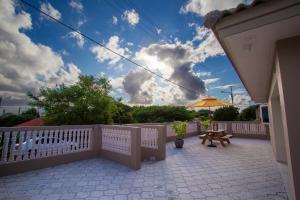 eine Terrasse mit einem weißen Zaun, einem Tisch und einem Sonnenschirm in der Unterkunft Lovely Caribbean family villa with private pool in Willemstad
