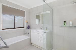 Un baño blanco con ducha y lavabo. en Fantastic Buddina Duplex, en Buddina