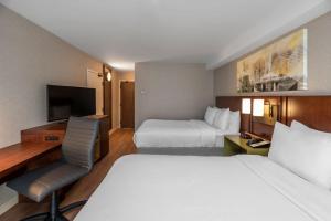 a hotel room with two beds and a desk and a television at Comfort Inn Hamilton/Stoney Creek in Hamilton