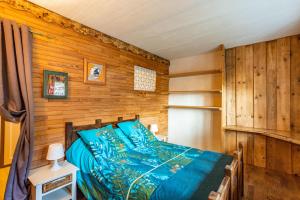 een slaapkamer met een blauw bed in een houten muur bij Aux Bois dHermy in Marnaz
