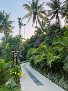a winding road with palm trees and a sign at Fab Valley Homestay in Munnar