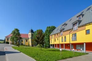 szereg kolorowych budynków na zielonym trawniku w obiekcie Apartman U Kostela w mieście Deštné v Orlických horách