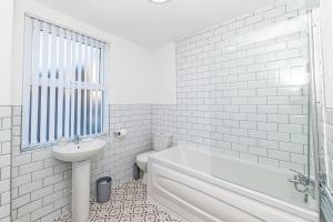 bagno bianco con lavandino, vasca e servizi igienici di 3 Bedroom Holiday Home within Kensington a Liverpool