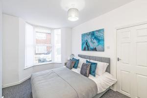 Dormitorio blanco con cama con almohadas azules en 3 Bedroom Holiday Home within Kensington en Liverpool