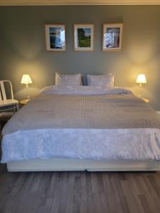 um quarto com uma cama grande com 2 candeeiros e 2 cadeiras em Bokskogens Guesthouse em Kulltorp