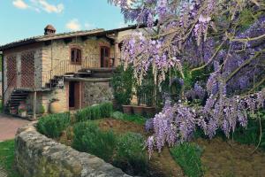 a house with a flowering tree in front of it at Molino in chianti in Mercatale Val Di Pesa