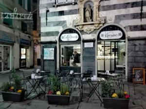 um restaurante com mesas e cadeiras em frente a um edifício em Old Town Guest House em Gênova