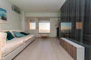 a living room with a white couch and a window at Turquoise Turtle Apartment - with seaview and A/C in Sesimbra