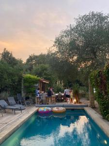 a backyard with a pool with people sitting around a table at Villa Bonheur Vallespir in Céret