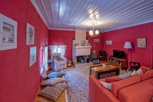 a living room with red walls and a couch and a table at Minodora's Guesthouse in Dikorfo