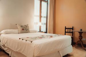 Cama blanca en habitación con ventana en Vieja Posada Hotel Histórico en Cafayate