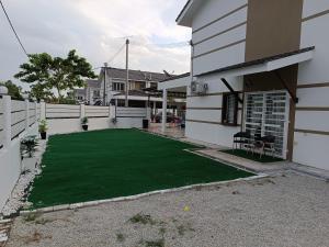 une arrière-cour avec une pelouse verte en face d'une maison dans l'établissement IN HOMESTAY CORNER BATU PAHAT, à Batu Pahat