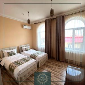 Una habitación de hotel con dos camas y una ventana. en Elite Boutique, en Samarkand