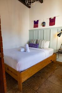 1 dormitorio con 1 cama con sábanas y almohadas blancas en Maya Papaya, en Antigua Guatemala