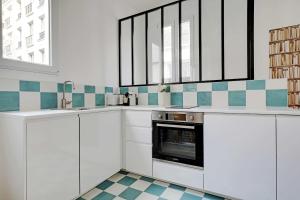 una cocina con armarios blancos y azulejos azules y blancos en Magnificent renovated apartment - Paris Expo Porte de Versailles en París
