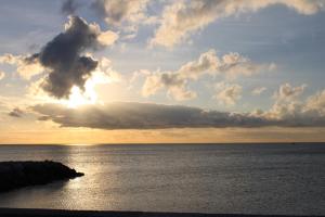 um pôr-do-sol sobre o oceano com o sol escondido atrás de uma nuvem em Hôtel La Villa des Oliviers em Cagnes-sur-Mer