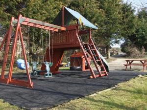 a playground with a slide and a swing at Cider Cottage in Hawkchurch