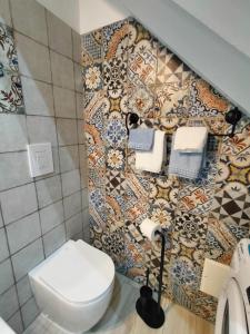 łazienka z toaletą i ścianą wyłożoną kafelkami w obiekcie VANNI 61 w Cefalù