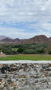 a stone wall with a view of a field and mountains at Alhara Lodge استراحة الحارة in Hatta
