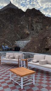 a group of white couches and a table and a mountain at Alhara Lodge استراحة الحارة 